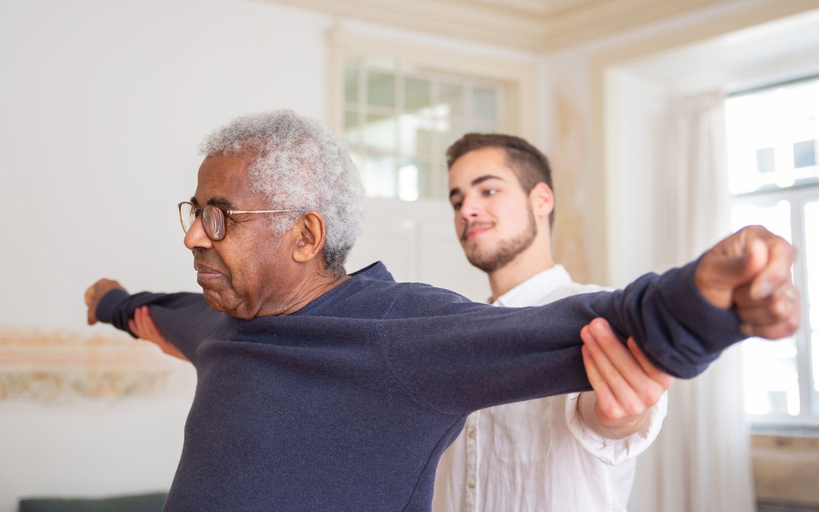 Physiotherapist assisting an elderly man with stretching exercises during geriatric physiotherapy
