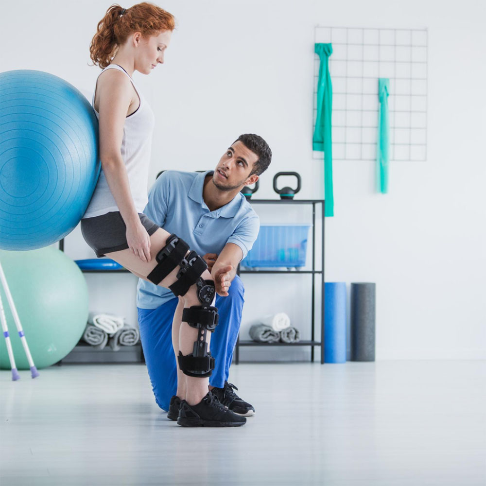 Sports physiotherapist applying kinesiology tape to a patient's back during orthopaedic rehabilitation