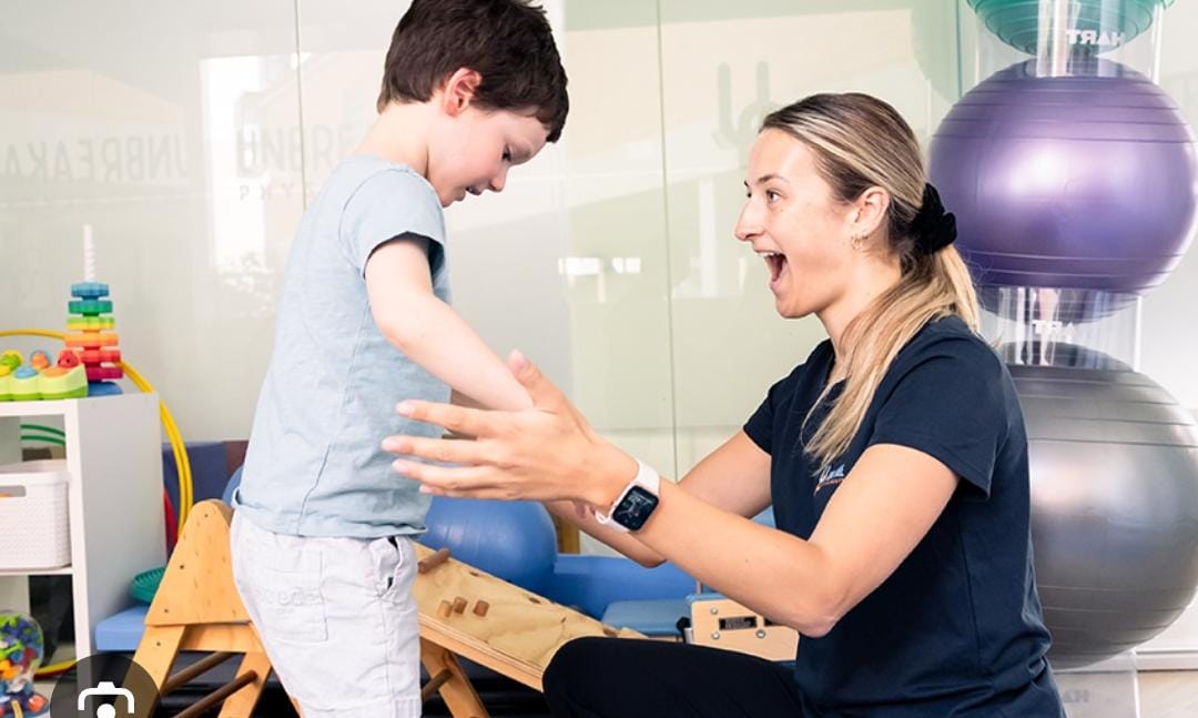 Physiotherapist assisting a young child learning to walk with a walker during paediatric rehabilitation